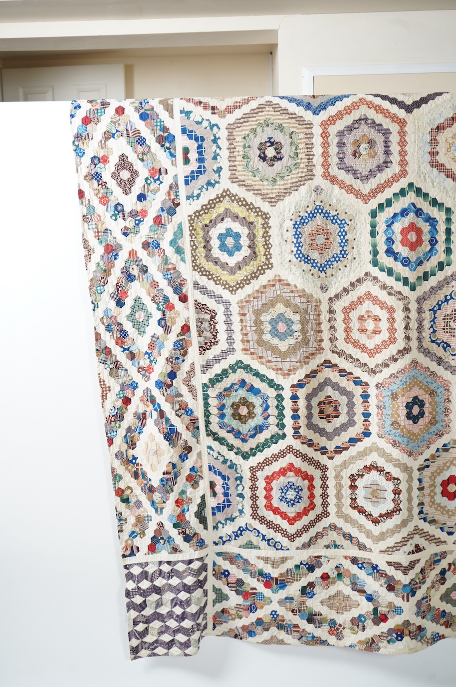 A large 19th century ‘Grandmother’s Flower Garden’ cotton patchwork bedspread, using dress fabric scraps from the day to create hexagonal concentric patterns which form a flower like shape/pattern, 282 x 254cm. Condition